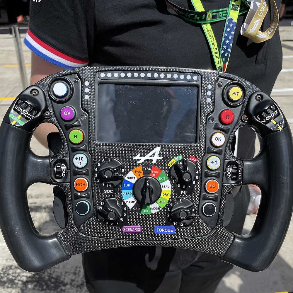 The steering wheel of a 2021 Alpine Formula 1 car: a screen, a row of shift lights and more than twenty buttons and dials.